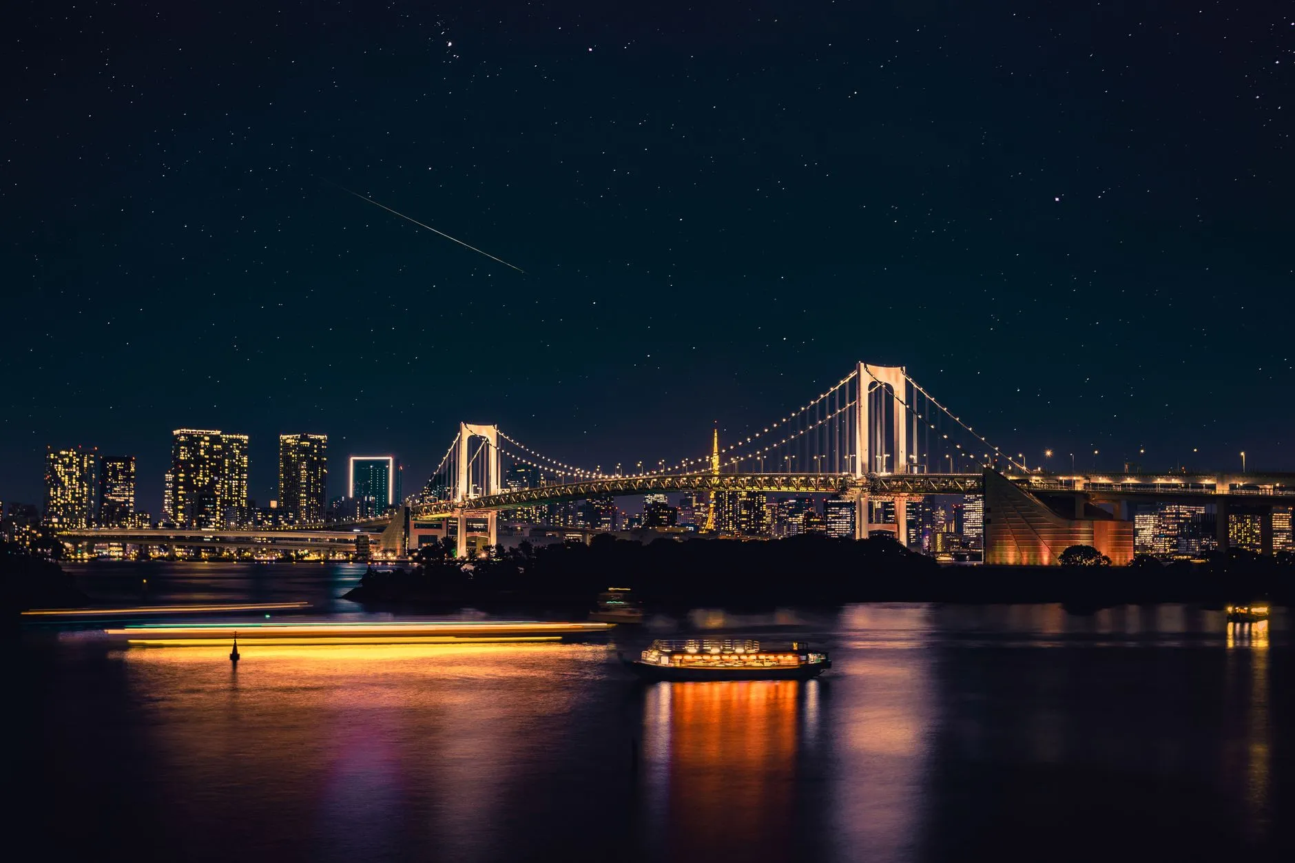 גשר הקשת של טוקיו (Rainbow Bridge) מואר בלילה מעל מפרץ טוקיו